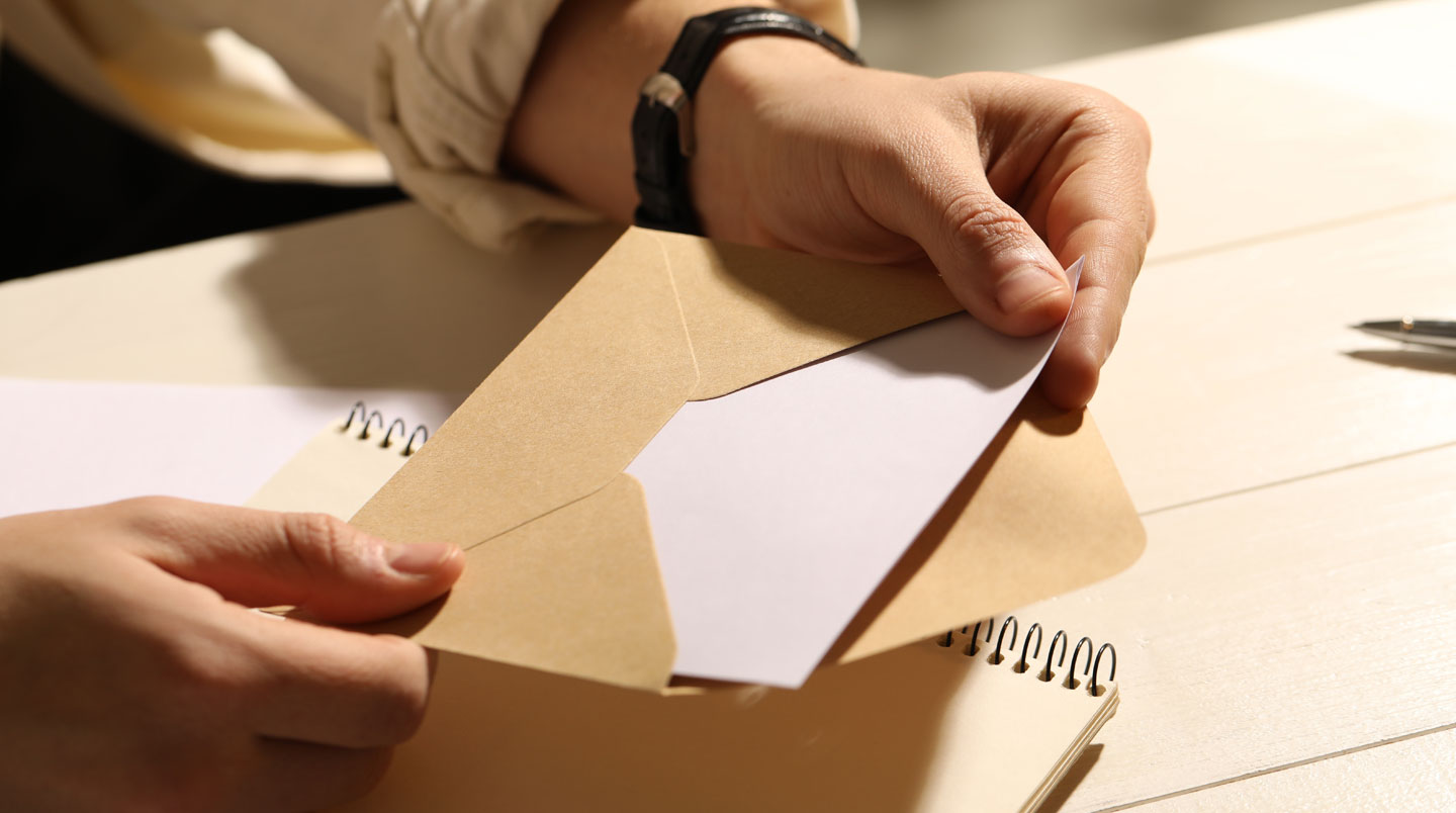 Personne déposant une enveloppe dans une boîte aux lettres jaune, geste symbolisant l'envoi d'une mise en demeure
